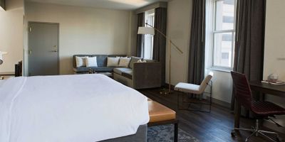 Hotel suite with king size bed, sectional sofa, desk and chair.