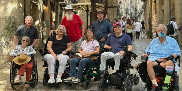 Group of wheelchair users posing for a picture on a Spanish street.