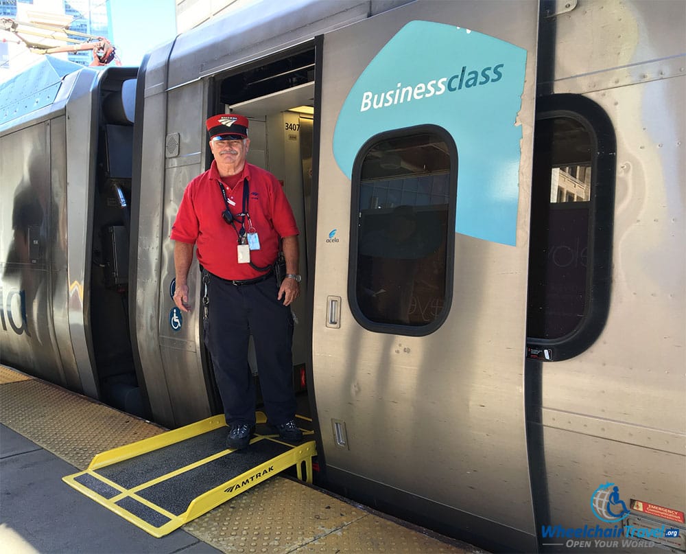 PHOTO: Wheelchair boarding ramp between platform and Acela train, with train conductor in frame.