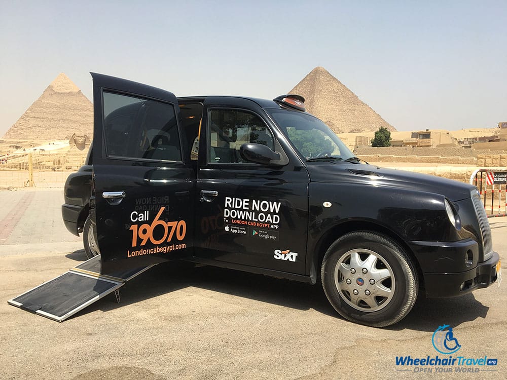 London Cab with wheelchair ramp extended in front of the Pyramids of Giza