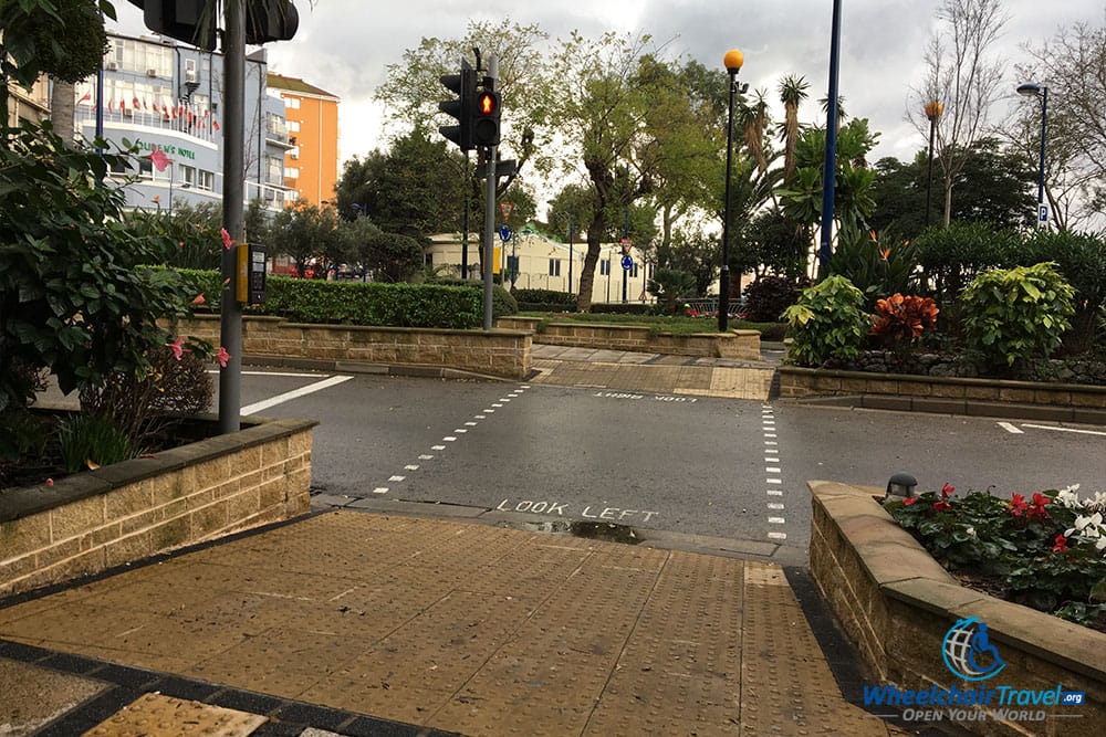 Gibraltar street crossing with curb ramp and traffic signals.