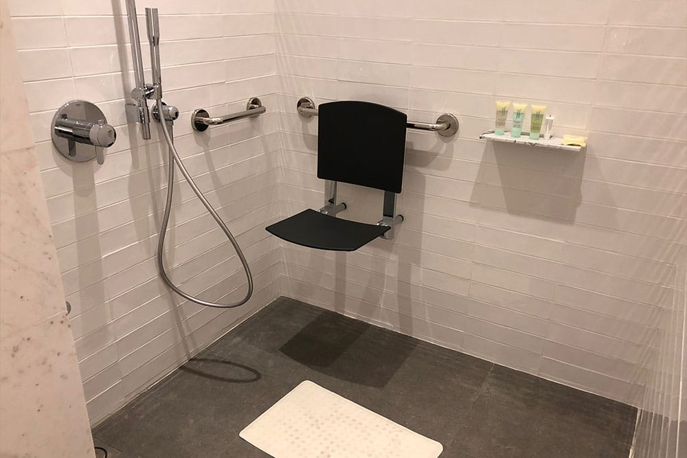 Shower chair relocated to a more accessible position in the roll-in shower.