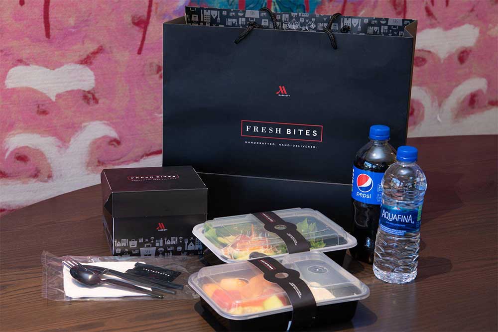 Food packaged in recyclable containers, pictured next to a bag with the Fresh Bites logo.