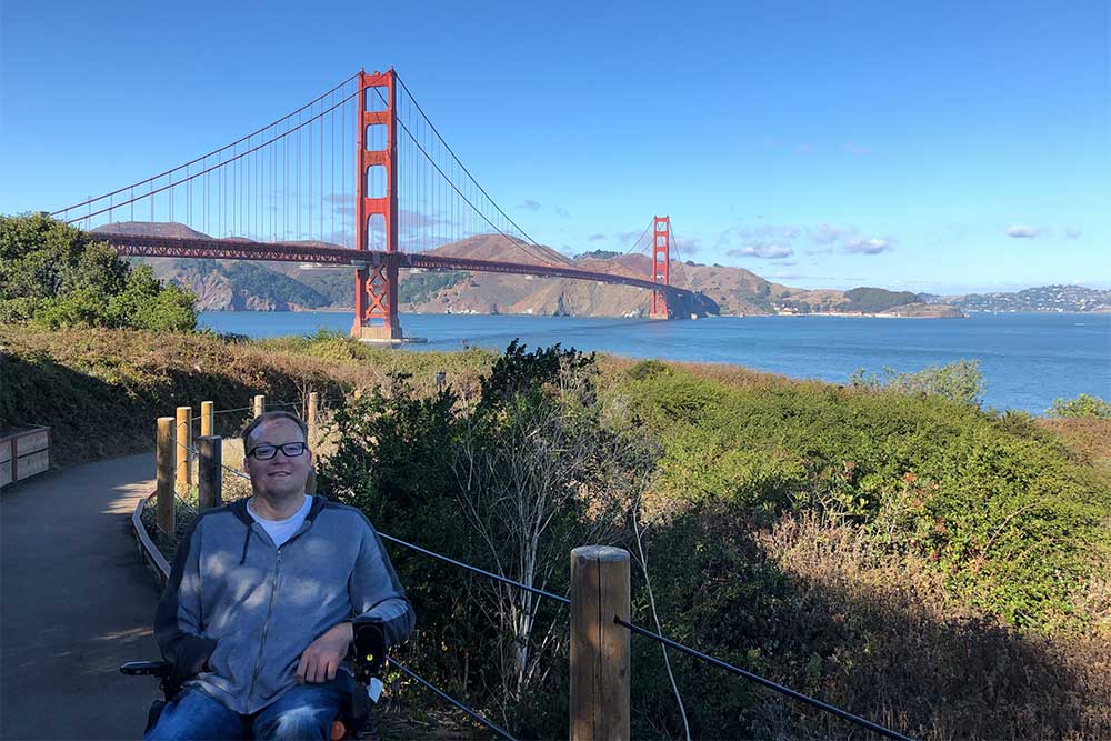 John in his wheelchair, pictured in front of the Golden Gate Bridge.