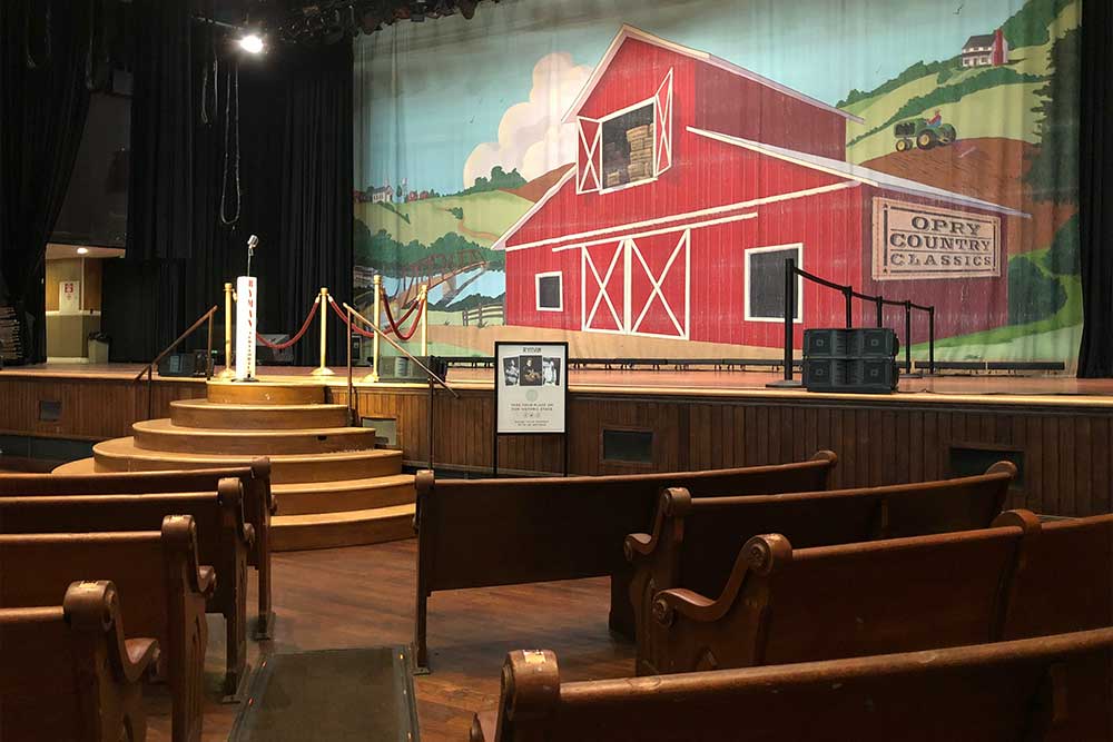 Wooden pew-style seating directly in front of the stage, with a space for wheelchairs.
