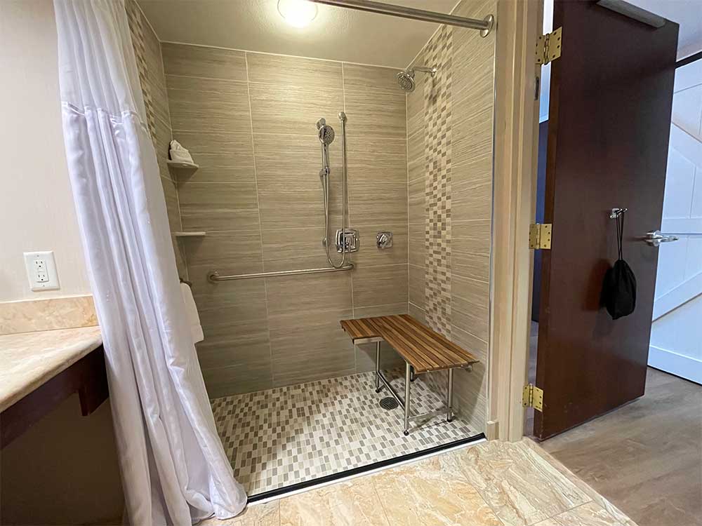 Roll-in shower with built-in seat and handheld showerhead.