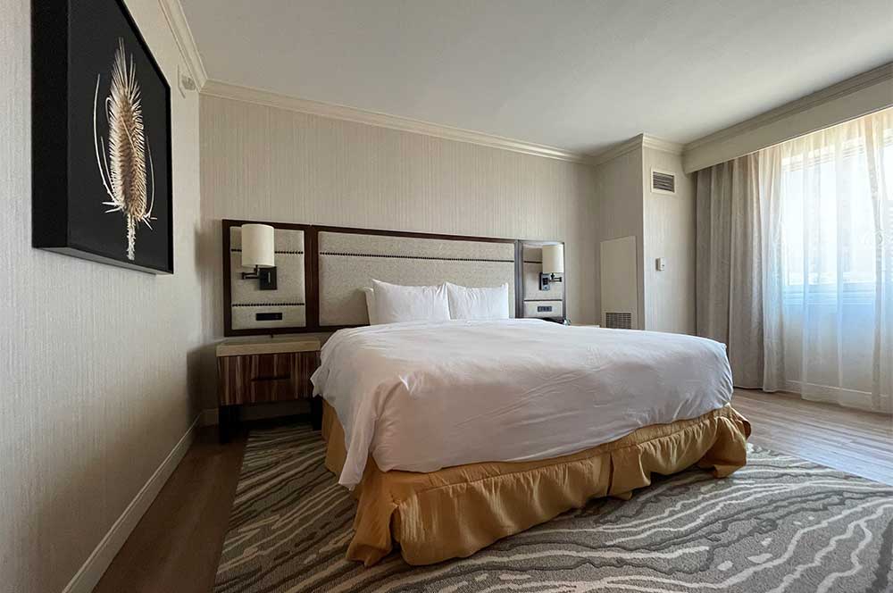 King size bed in center of room with wall mounted lamps on each side.