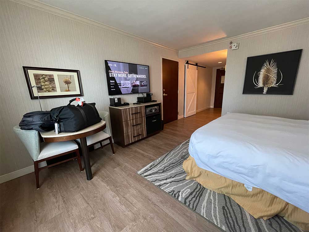 Large guest room with flat screen TV, table and other features.