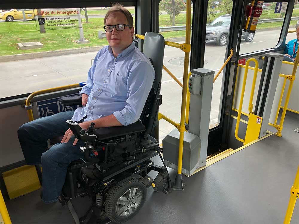Wheelchair user in designated wheelchair space on city bus.