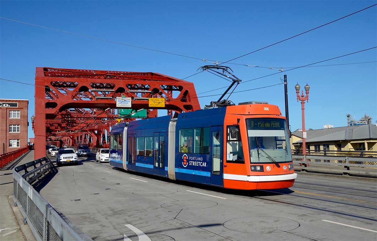 Portland streetcar crossing bridge in roadway with other cars.