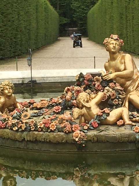 Golf cart beyond a fountain in a garden.