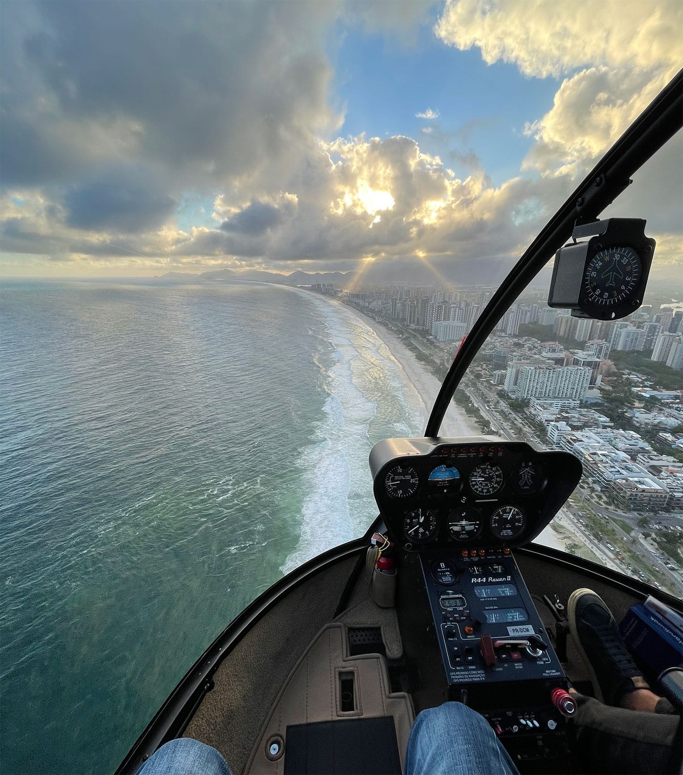 View of beach and crashing waves from the helicopter, with the sun beginning to set.