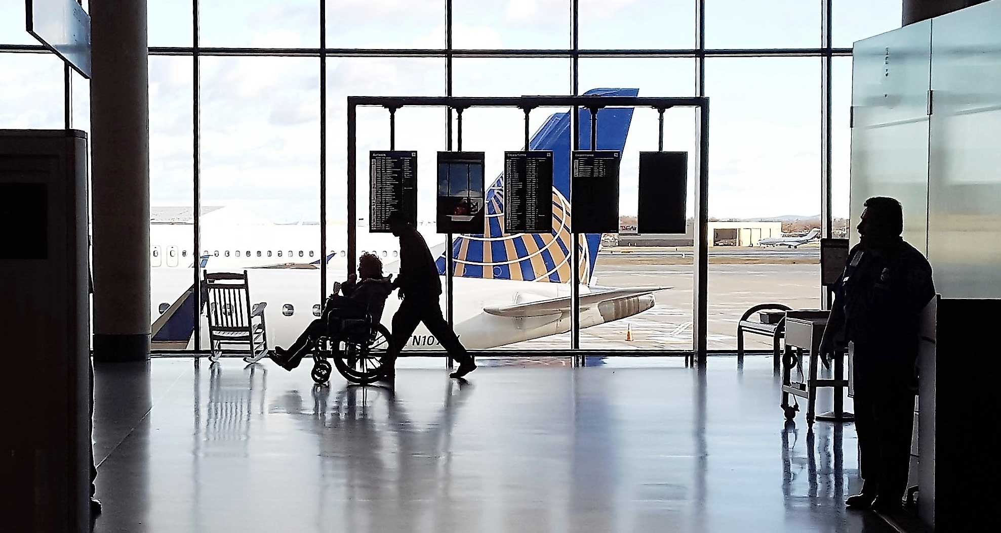 Disabled and elderly passenger being pushed through the airport terminal in a wheelchair.
