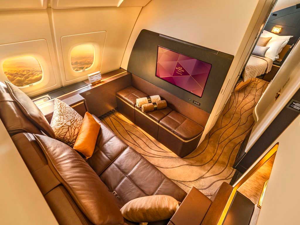 Large seating area with view into separate bedroom suite on airplane.