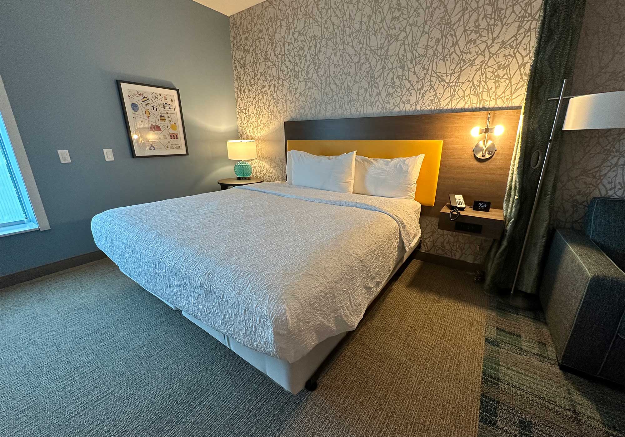 King size bed in carpeted hotel room.