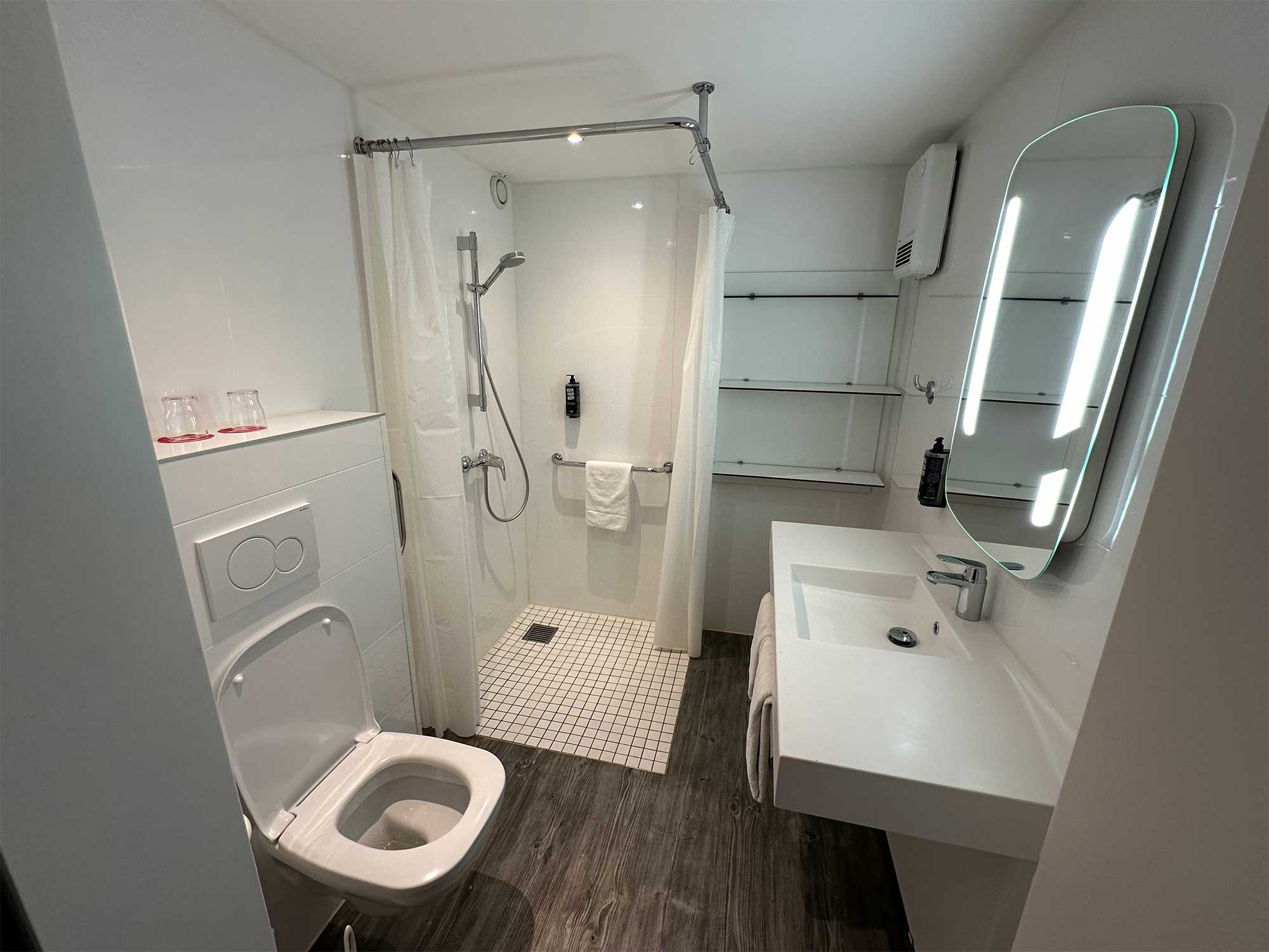 Bathroom with sink and toilet very close together just inside the entryway, with a narrow path to pass unsuitable for wheelchairs.
