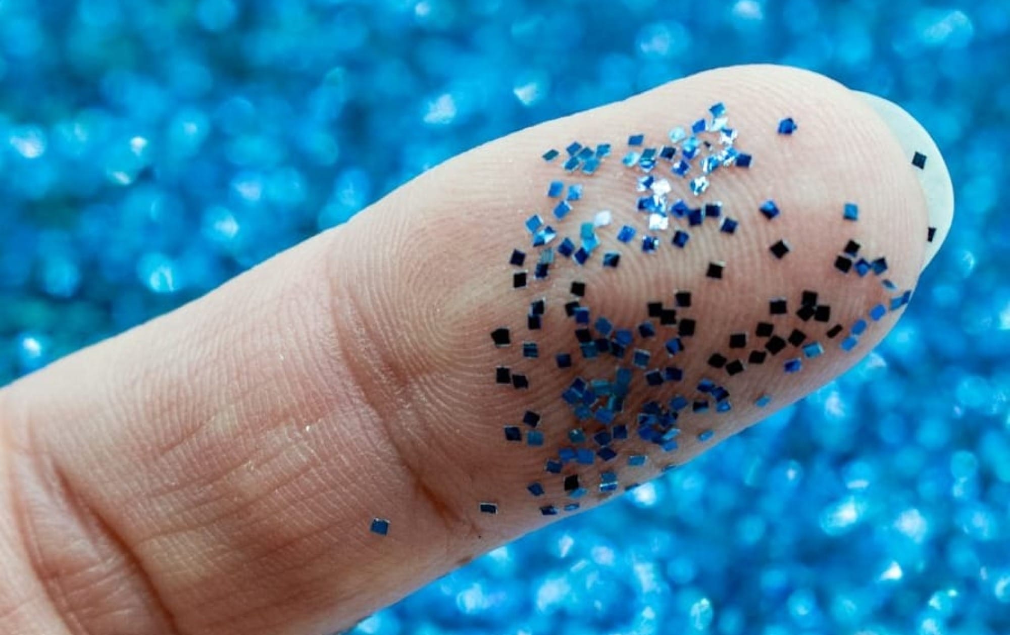 a finger with blue glitter on it and a blue background