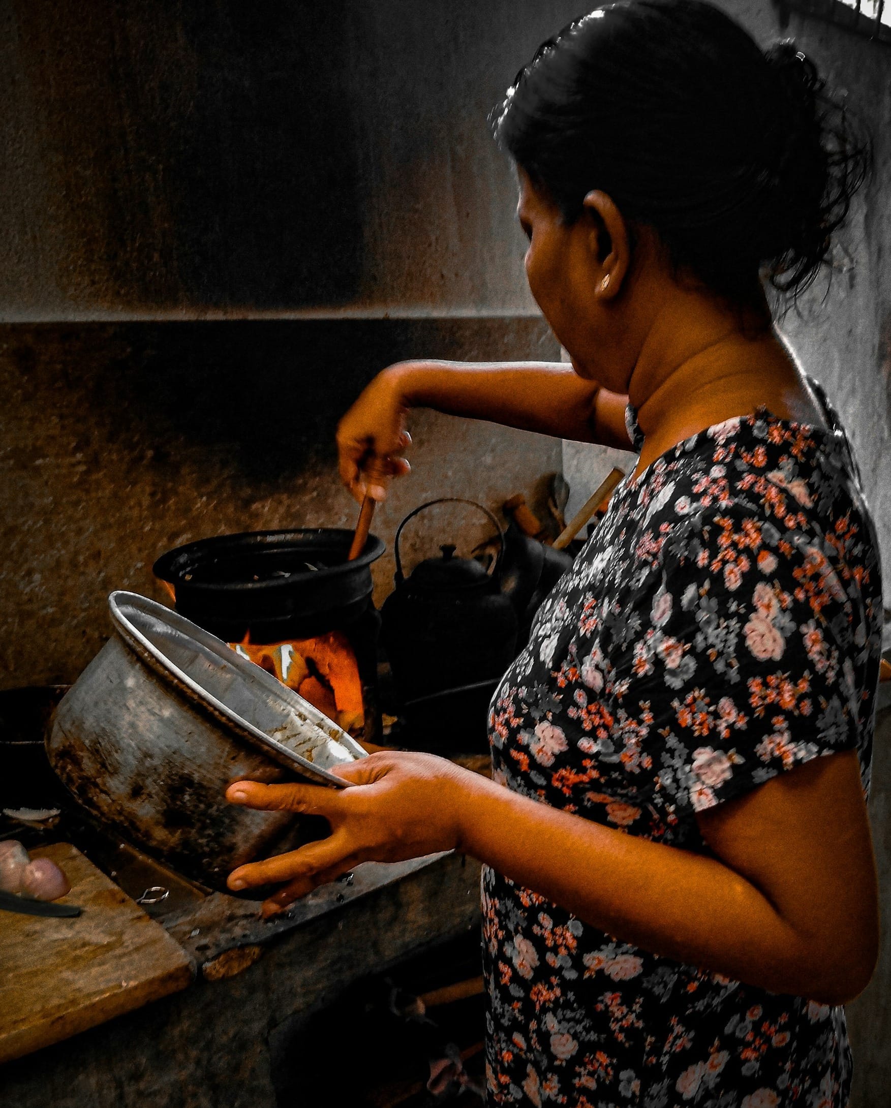 a woman cooking food in a pot on a stove