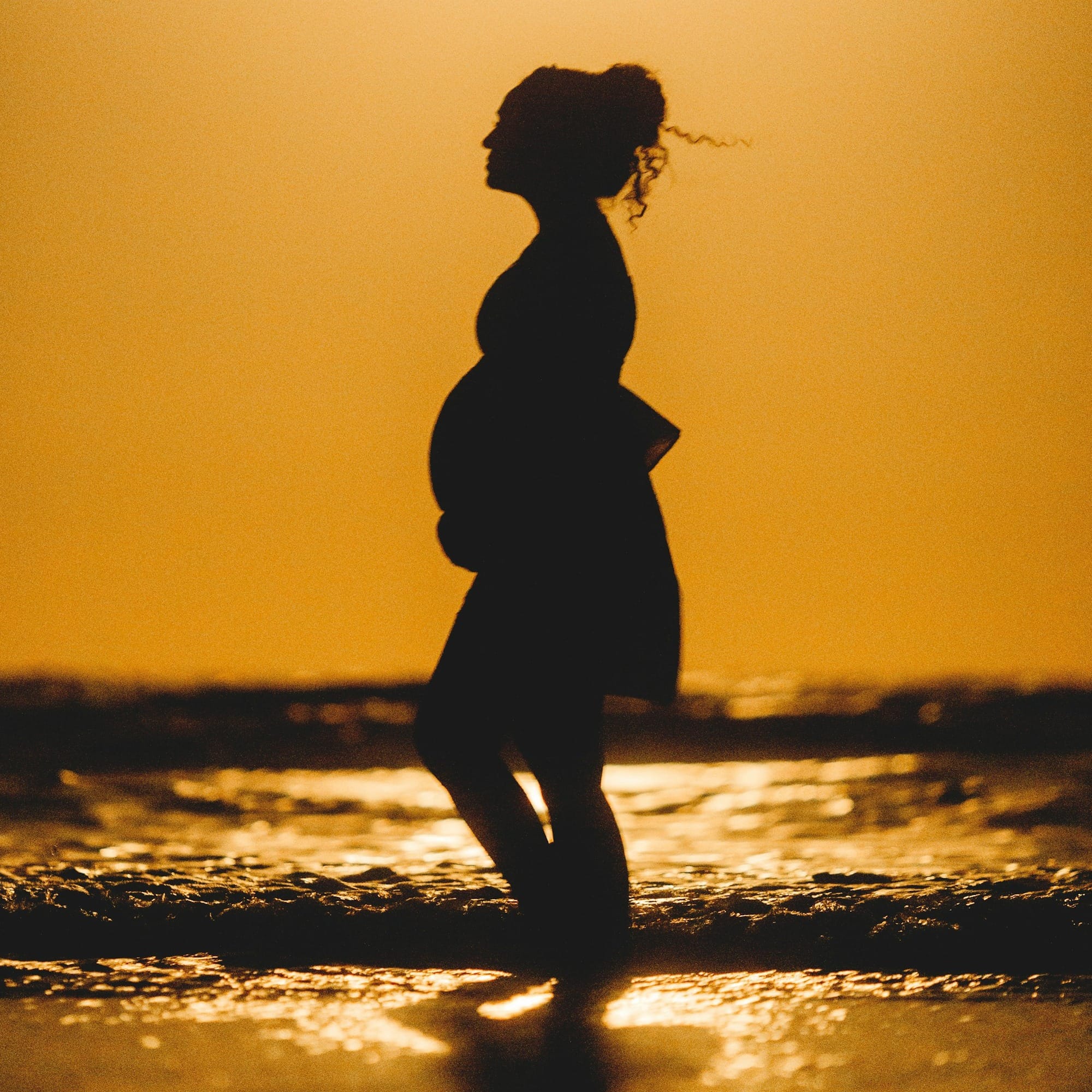 silhouette of woman standing on beach during sunset