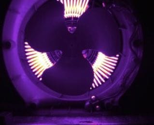 Thermal image of a spinning fan with distinct dark blades in front of bright heating coils.