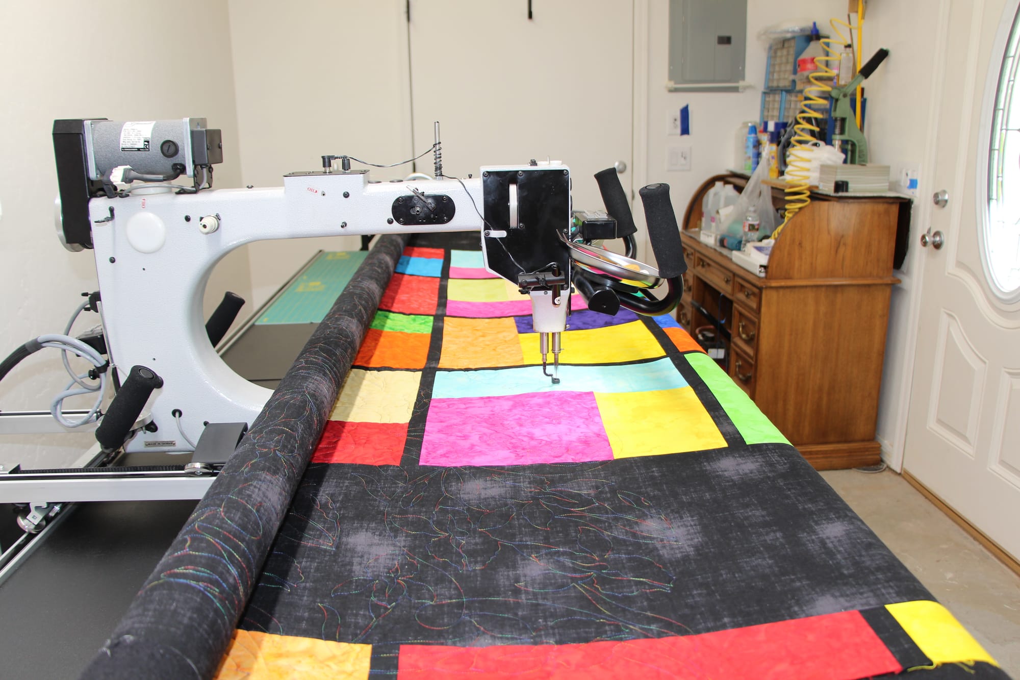 Debs Quilt studio expertly finishing this quilt top on my longarm. Very bright multi-colored squares, rectangles with sashing between the blocks. Background fabric is black and so is the back of the quilt.