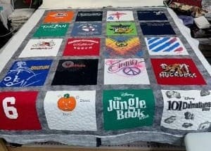 A colorful quilt made from various t-shirts and fabric items, showcasing memories and creativity in textile form.