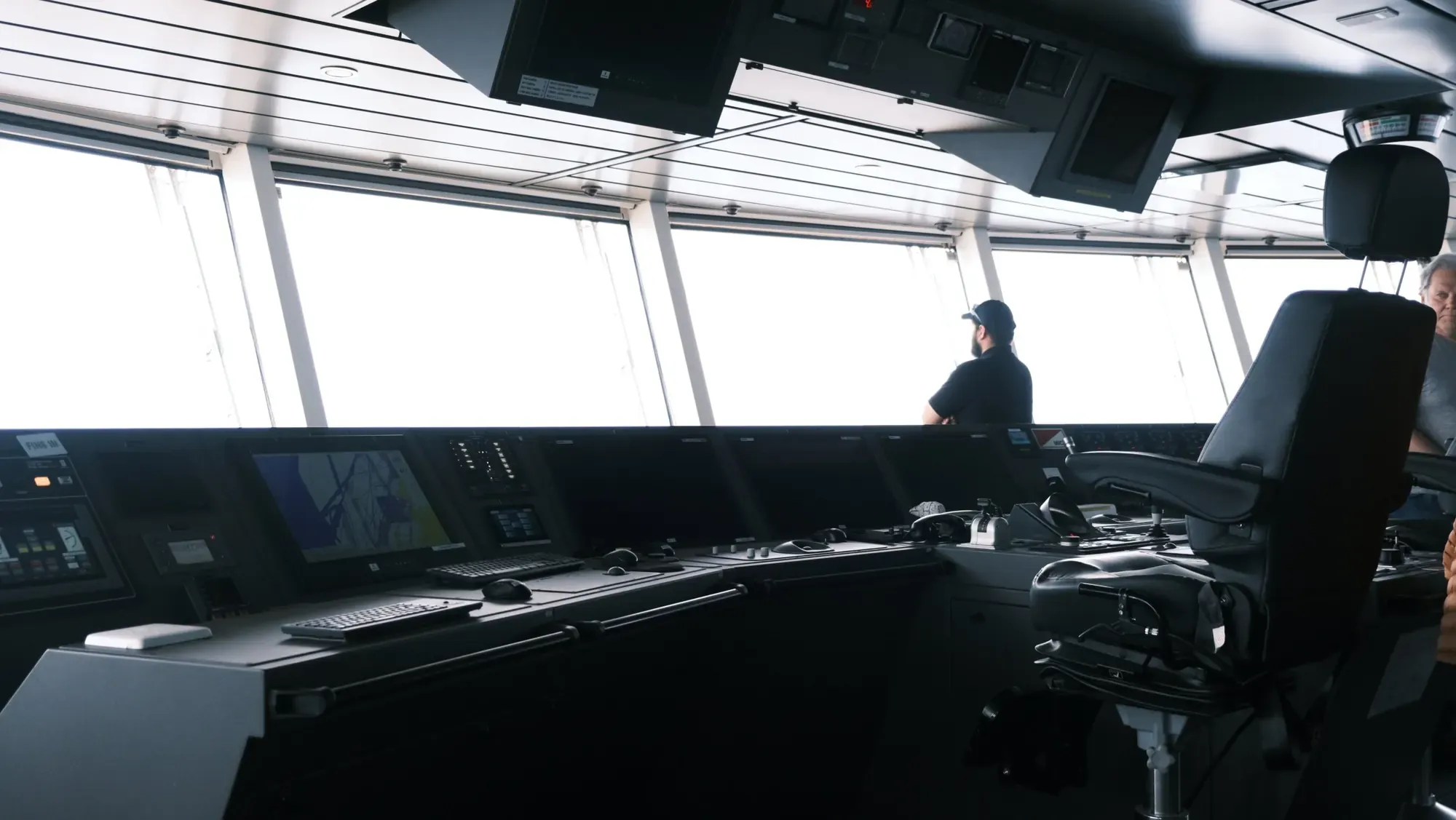 Brücke des Expeditionsschiffs mit Bildschirmen, Steuerpult und Kapitänsstuhl, ein Offizier schaut aus dem Fenster