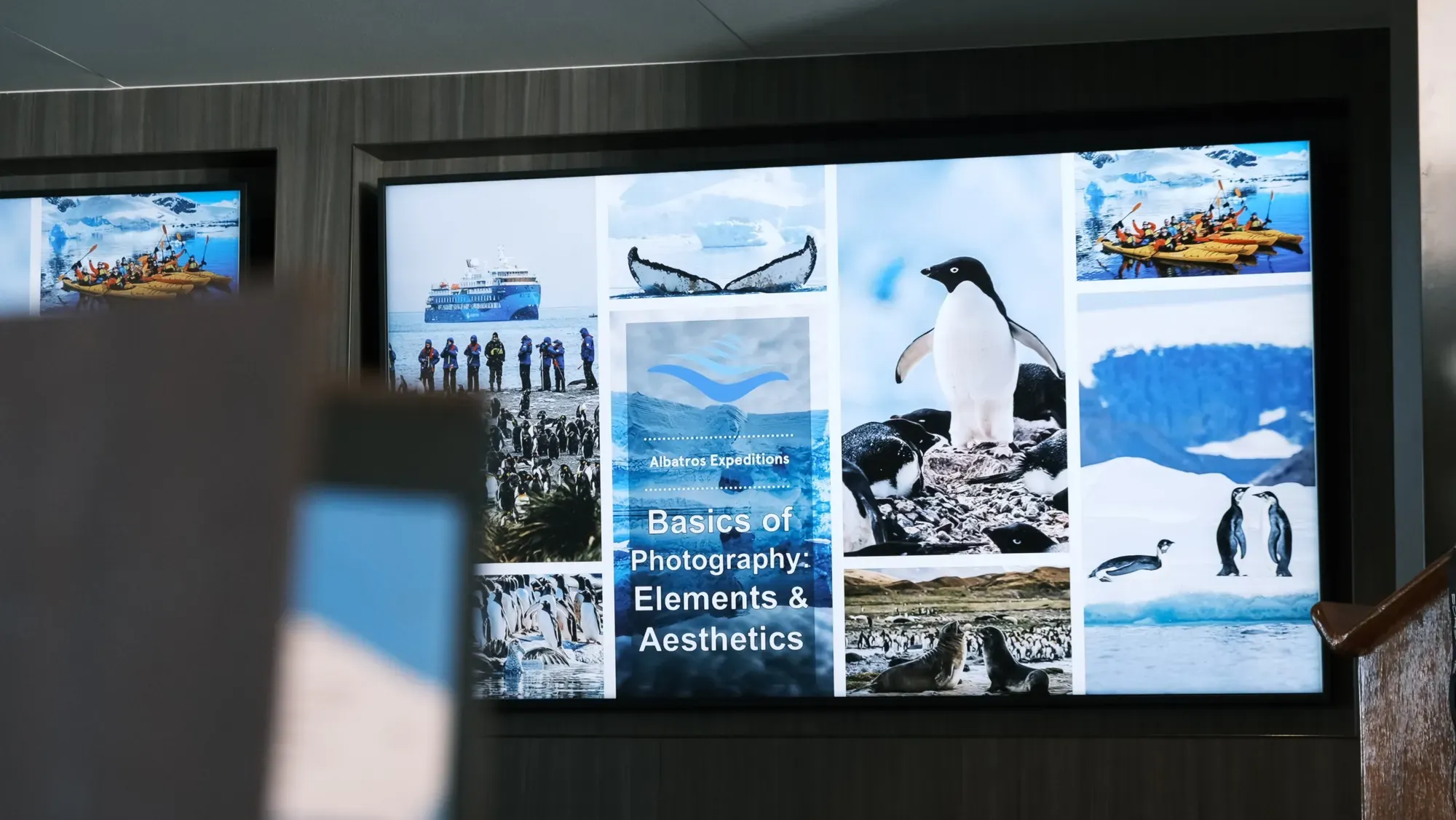 Bildschirm mit dem Vortrag «Basics of Photography» von Albatros Expeditions im Vortragssaal des Schiffs