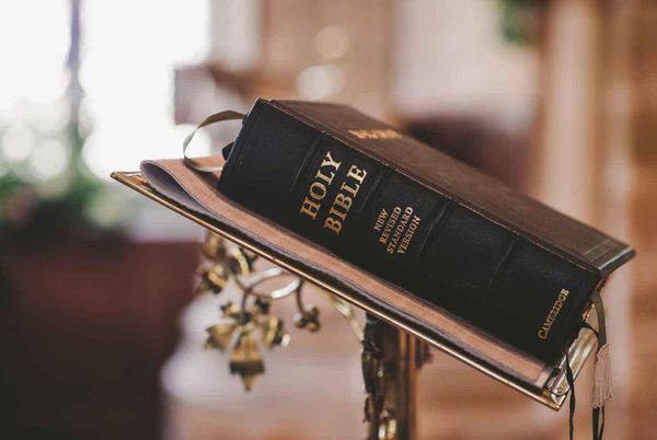 Bible on a stand with closed cover and bookmark.  Black leather Bible.