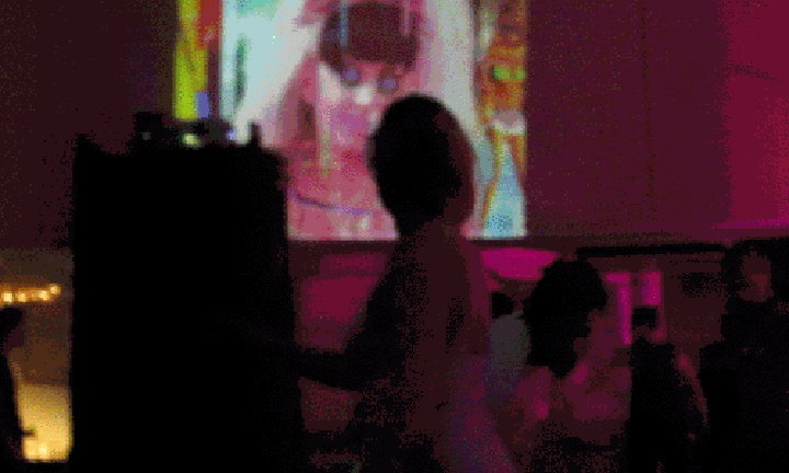In a darkened theatre, back-lit bodies dance in front of a GIF work featuring Lady Gaga.