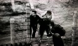Young East Germans risking their lives by crossing a barbwire fence that was part of the many barriers of the "Berlin Wall."