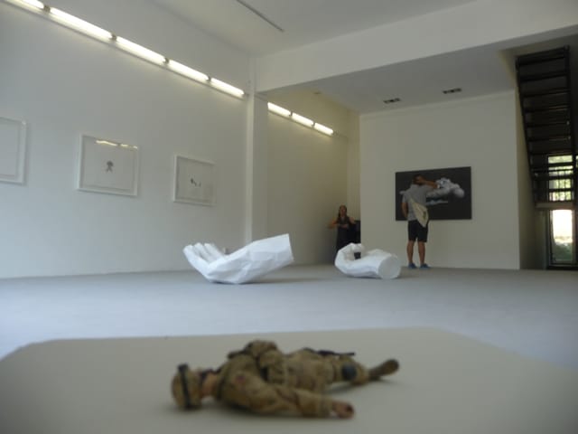 An America's Army action figure composed of multiple action figures' parts lies in the corner of the exhibition.