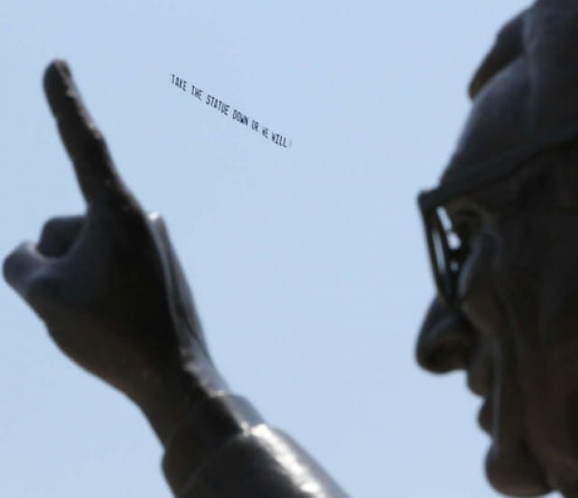 A banner reading, "Take the Statue Down or We Will" was flown over the Paterno statue in Pennsylvania. Image by Michael Bryant of the Inquirer,