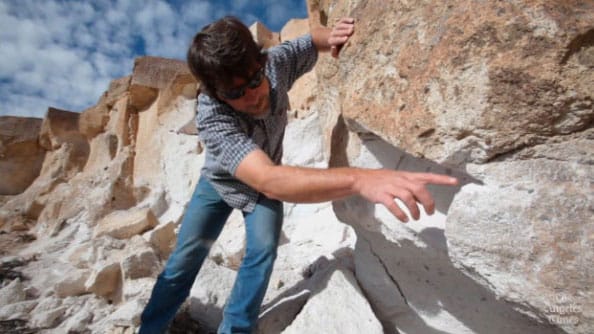 Archaeologist Greg Haverstock pointing out a spot where thieves cut the petroglyphs from the rock