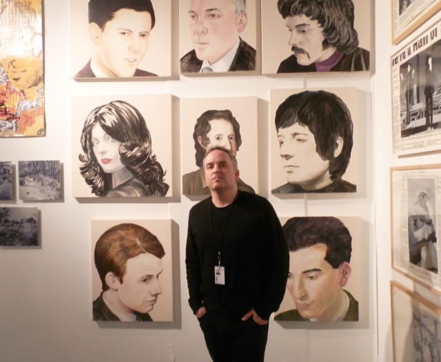 Artist Noah Becker poses with his paintings at the Whitehot Presents booth 