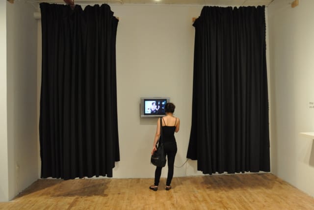 A visitor watches a video at Chloë Bass's The Bureau of Self-Recognition exhibition at Momenta Art.