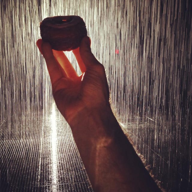 This photo that Dominique Ansel tweeted of a cronut held up inside the Rain Room captures the insanity of summertime trend waiting. (photo by Dominique Ansel on Twitter)