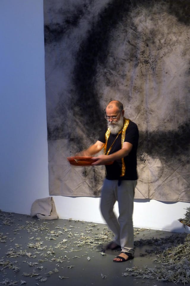AA Bronson scattering sage on the floor of a gallery at "The Temptation of AA Bronson" (photo courtesy Matthias Herrmann)