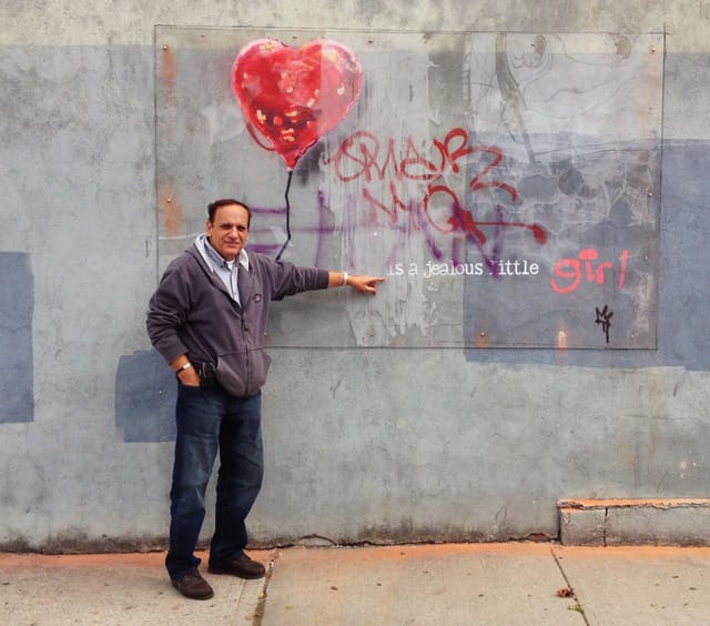Vassilio Georgiadis with his protected Banksy in Red Hook. (photo for Hyperallergic)