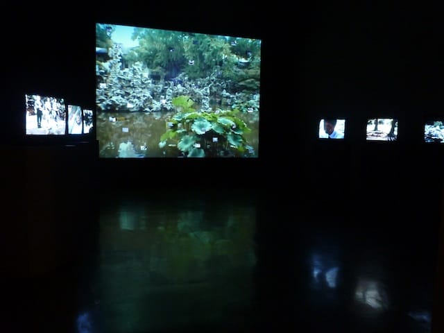 The Tonight Moon installation, with a projection, tv monitors and tiny LCD screens embedded in the projection wall. Images by the author for Hyperallergic.