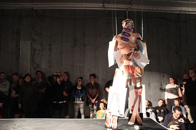 Rocio Boliver starts the performance by posing with photographs that depict the female body. (all photos by the author for Hyperallergic)