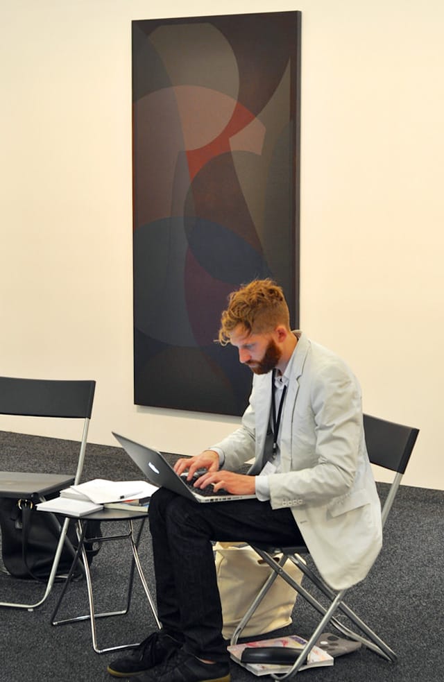 A painting by Halsey Hathaway hangs in Rawson Projects's booth with gallerist Christ Rawson in the foreground.