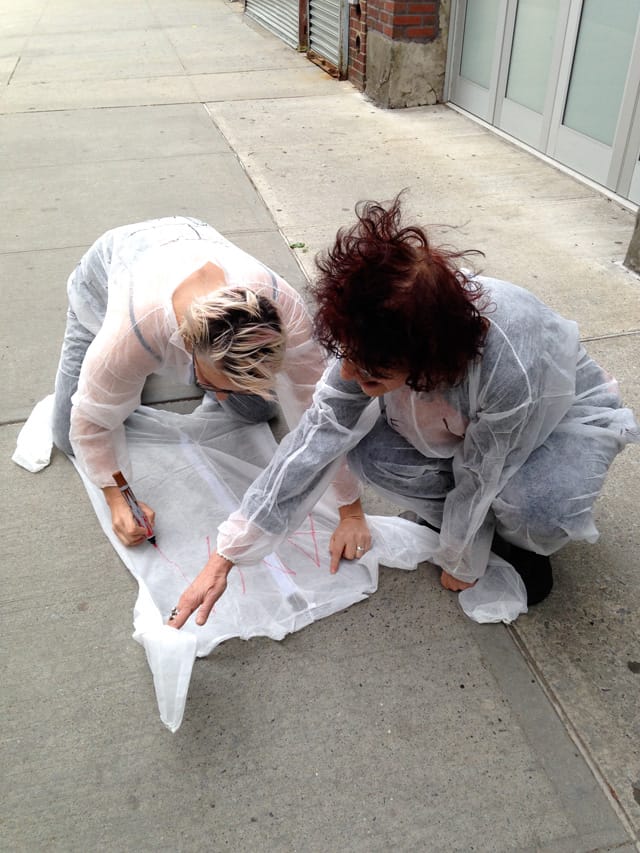 Christen Clifford (left) and Karen Malpede (right) writing on a jumpsuit (click to enlarge)