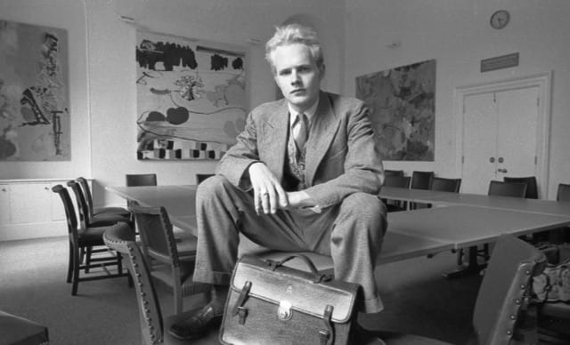 Joshua Compston in a publicity photograph for ‘The Courtauld Loan Collection’ (1991). Works in the background are by Piers Wardle (left), Fiona Rae (center) and David Taborn (right). (photo © Guy Moberly)