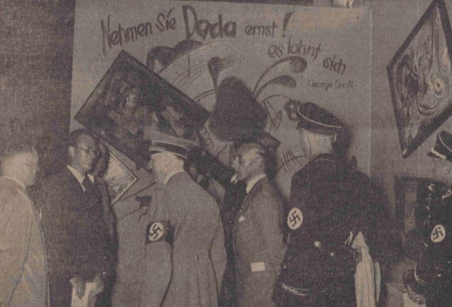 Adolf Hitler and other Nazi officials (Hoffmann, Willrich, Hansen, and Ziegler) standing by the Dada wall at the 'Entartete Kunst' (Degenerate Art) exhibition, July 16, 1937. Paintings by Vasily Kandinsky, Paul Klee, and Kurt Schwitters have been deliberately hung askew and are accompanied by a slogan penned by George Grosz. This photo was published in the Nationalist Observer, South German (Süddeutsche) issue, No. 199, July 18, 1937. (Staatsbibliothek zu Berlin Stiftung Preussischer Kulturbesitz, Berlin, Germany; bpk, Berlin, Art Resource, NY)