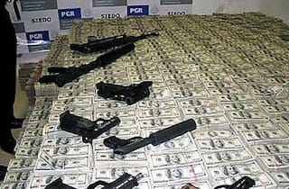 Drug money and weapons seized by the DEA in 2007 (image via Wikimedia) 