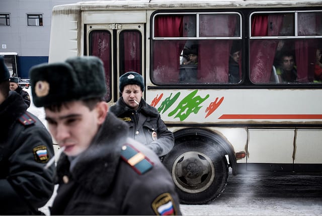 Police in Vnukovo after raiding and detaining several dozen labor migrant from Central Asia, who wait in the bus behind. 