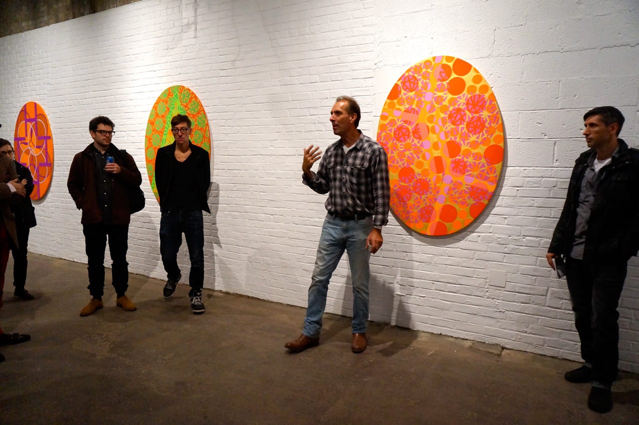 TK speaking to visitors at ArtHelix, with work by Mari Rantanen in the background