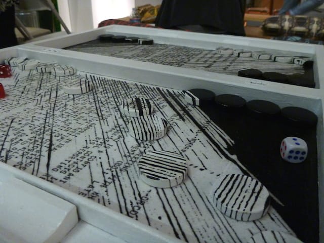 According to the artist statement, Gelare Khoshgozaran's Convergences is a backgammon board whose background contains pieces of "archives from the US Iran-Contra documents collected and restructured after the occupation of the US Embassy by the Iranian Revolutionary Students in 1980 Tehran." The checkers start camouflaged in the board and over time, the messages are distorted and shifted as the game commences.