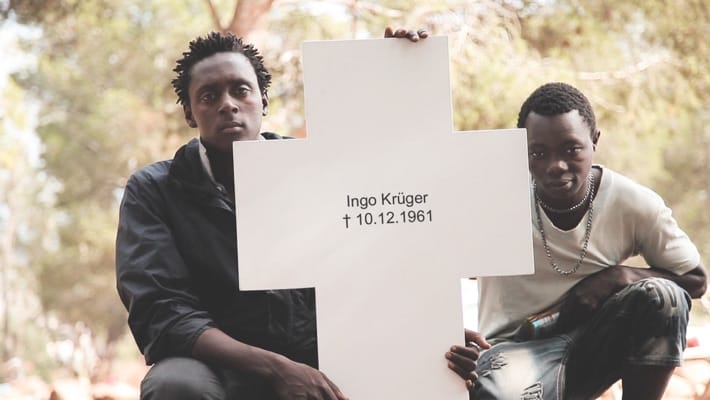 A migrant holds one of the crosses (Image courtesy of the Center for Political Beauty)